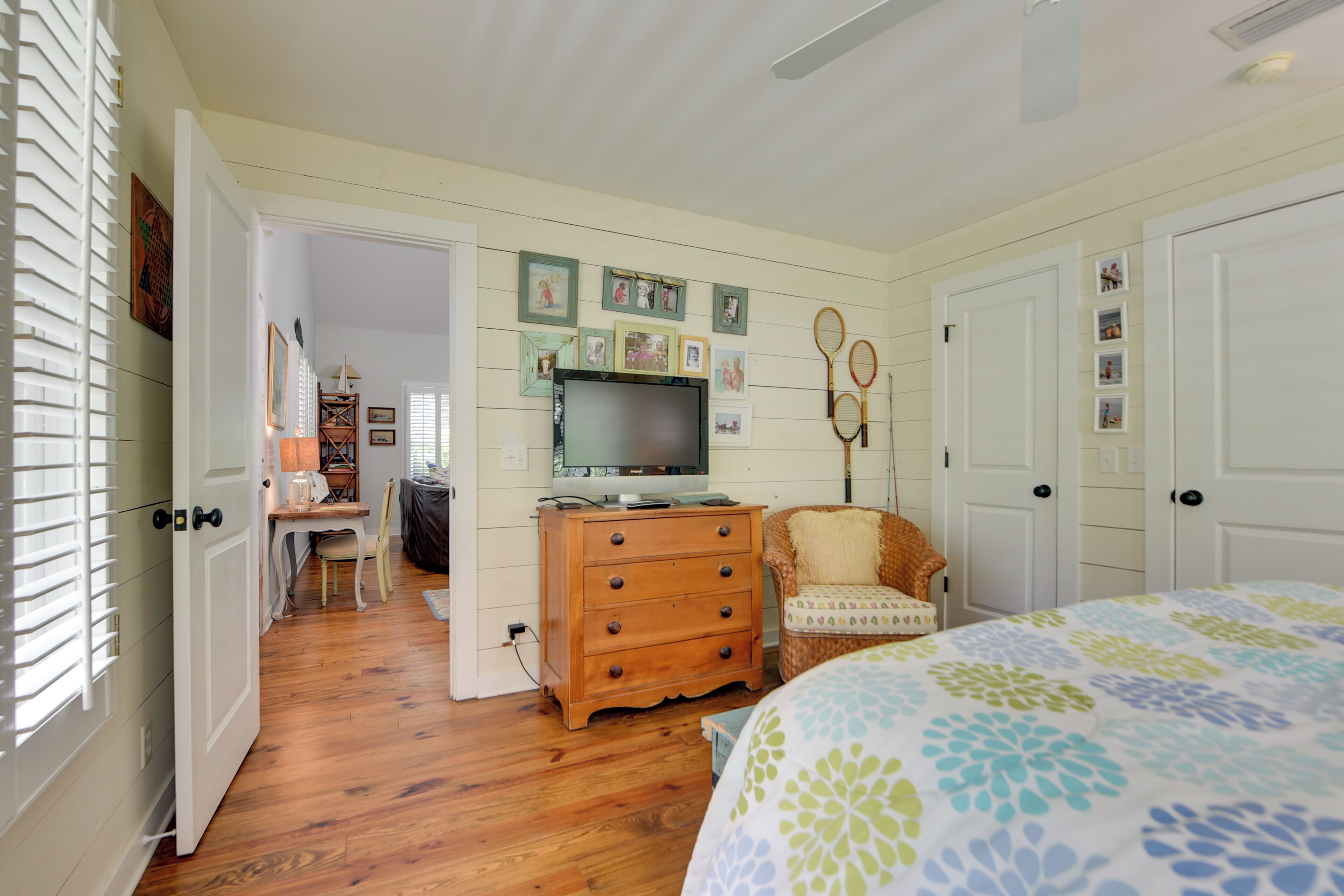 A bedroom with a bed, wooden dresser, television, and framed pictures on the wall.