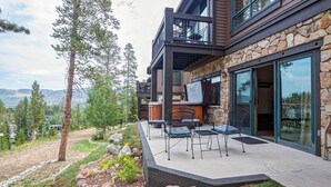 A modern house with a stone facade, a deck with outdoor furniture, and a view of the mountains. - Private Hot Tub, Ski-in/ski-out! (Breckenridge)