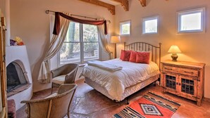 Ein gemütliches Schlafzimmer mit einem Bett, einem Sessel, einem Kamin und einem Nachttisch mit Lampe.
