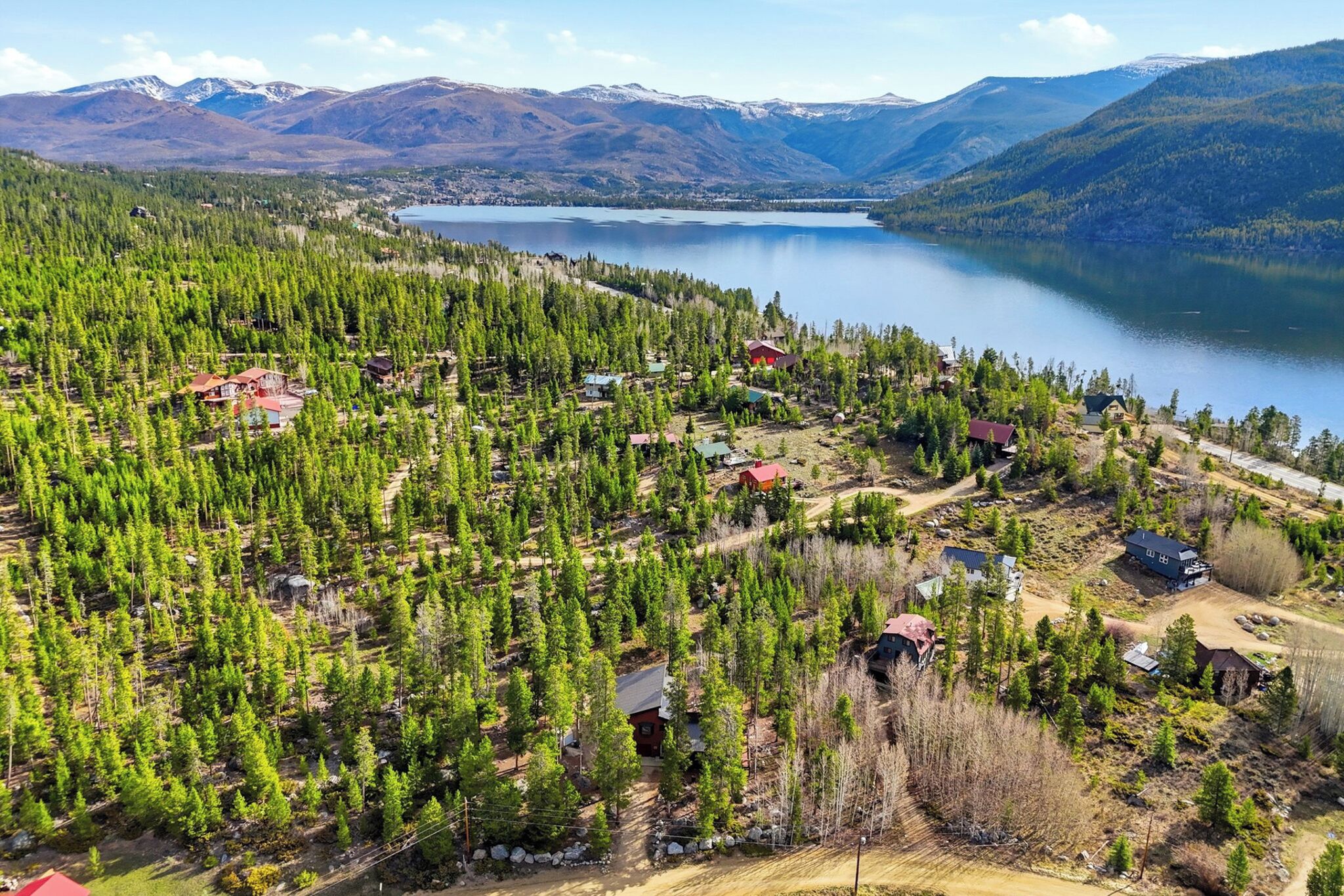 A forested area with several cabins and a lake in the background.