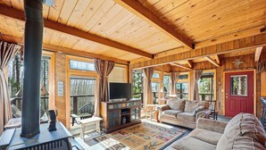 L’intérieur d’un chalet confortable, avec une cheminée, un téléviseur, un canapé et un tapis.