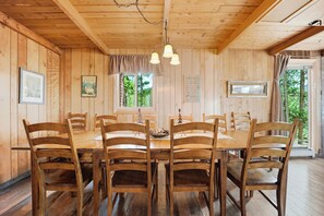 A wooden cabin with a dining table surrounded by chairs, a chandelier, and a window with a view of trees. - Large Home on 1 Acre: 2 Mi to Grand Lake Village (Grand Lake)