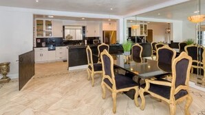 A modern kitchen with a central island, dark wooden chairs, and a dining table. - Luxurious 3-Bedroom Westwood Gem  (Los Angeles)