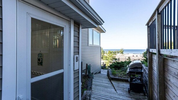 A wooden deck leading to a house with a view of the beach.