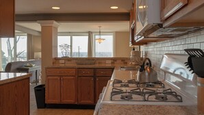 A kitchen with wooden cabinets, a gas stove, and a large window.