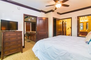 Habitación de hotel con cama, cómoda, televisión y ventilador de techo.