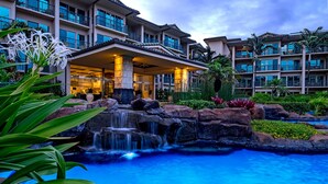 Ein Hotel mit Pool, Wasserfall und üppiger Bepflanzung.