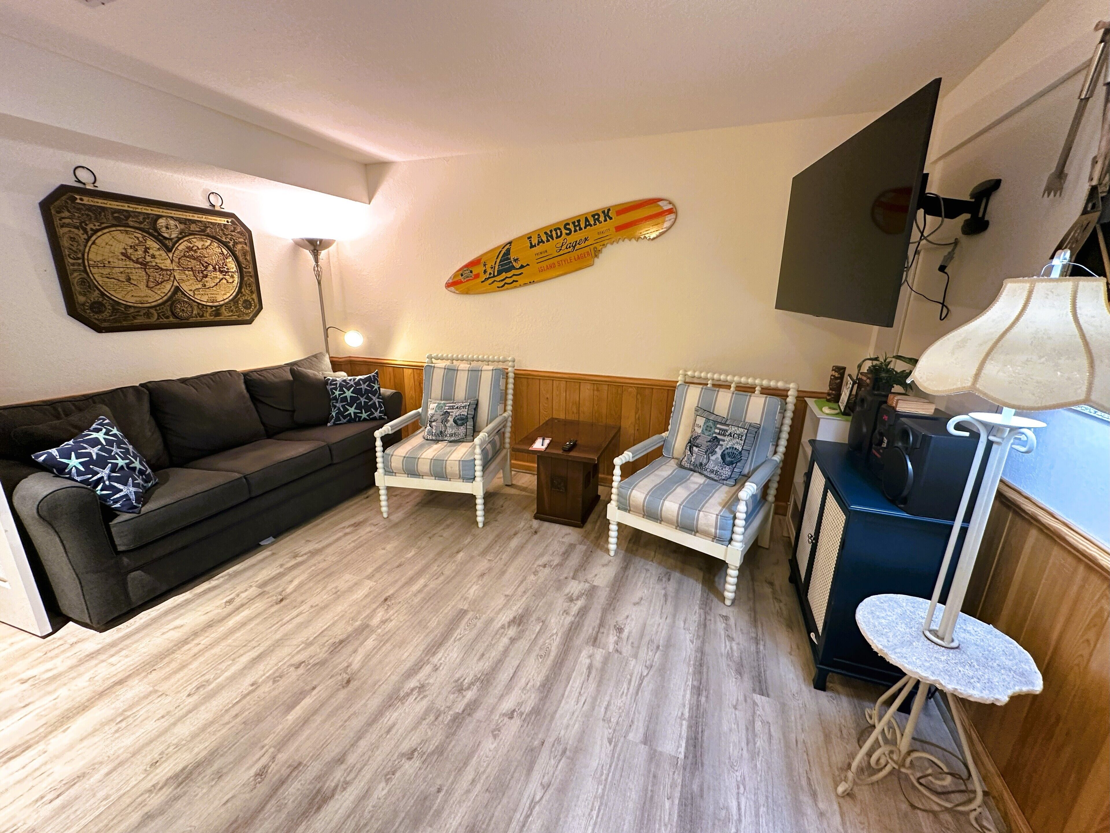 Ein Wohnzimmer mit einer schwarzen Couch, zwei gestreiften Sesseln, einem kleinen Tisch und einer Lampe.