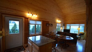 Interior de una cabaña de madera con cocina, comedor y sala de estar.