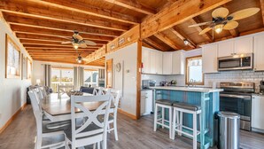 A spacious kitchen with white cabinets, a blue island, and stainless steel appliances. - Duck Life - Oceanside, Sound View, 325 Yards to Beach, Pool, Hot Tub, Tiki Bar, Pool Table, Pets OK (Duck)