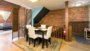 A dining area with a brick wall, wooden staircase, and a table with chairs.