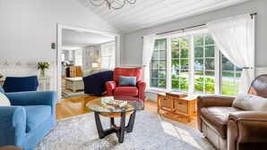 A spacious living room with a large window, a chandelier, and a view of the outdoors.