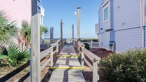 Un muelle de madera que conduce a un edificio de fachada azul.