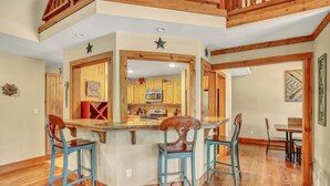 A kitchen with wooden cabinets, a microwave, and a bar area with stools. - Secluded Cabin for 10 guests with Pool, Hot Tub, and Fire Pit (Wimberley)