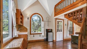 A spacious loft bedroom with a large skylight, wooden beams, and a view of the outdoors. - Secluded Cabin for 10 guests with Pool, Hot Tub, and Fire Pit (Wimberley)