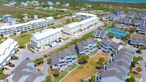 A coastal residential area with multi-story buildings, a tennis court, and a view of the ocean. - Gated Community, Pool, Green Space, Great Beach Access - SeaCliff (Cape San Blas)