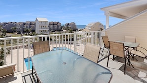 A balcony with a glass table and chairs, overlooking a pool and a beachfront community. - Gated Community, Pool, Green Space, Great Beach Access - SeaCliff (Cape San Blas)