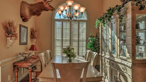 A dining room with a large table, chairs, a chandelier, and a mounted deer head. - Walk to Marina! Midway House by Sunbury Channel (Midway)