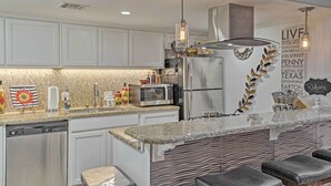 A modern kitchen with white cabinets, granite countertops, stainless steel appliances, and a bar area with leather stools. - 5 Mi to Dtwn: Austin Gem w/ Pool, Pets Welcome (Austin)