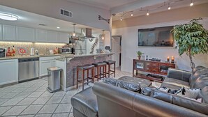 A modern kitchen with a central island, bar stools, and a seating area with a leather sofa and a coffee table. - 5 Mi to Dtwn: Austin Gem w/ Pool, Pets Welcome (Austin)