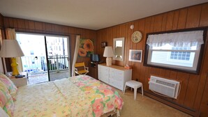 A bedroom with a bed, dresser, chair, and a window with a view. - Spacious, yet cozy 3 bedroom condo with free WiFi and a balcony located midtown on the ocean block just a short walk to the beach! (Ocean City)