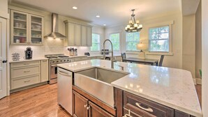 A spacious kitchen with white cabinetry, a large island, and a stainless steel range hood. - 2 Mi to Dtwn: Home in NoDa District Near UNC! (Charlotte)