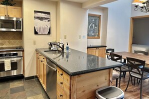 A modern kitchen with a central island, stainless steel appliances, and wooden cabinetry.