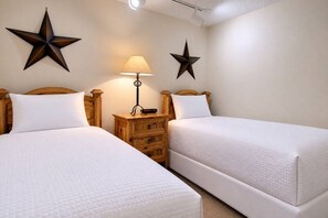 A hotel room with two beds, a nightstand, a lamp, and two star-shaped wall decorations.