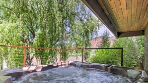 Ein Whirlpool mit Holzdach, umgeben von üppigem Grün und einem Metallzaun.