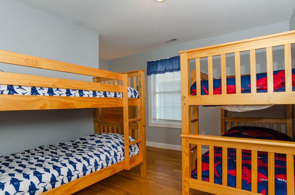 Ein Zimmer mit zwei Etagenbetten, eines mit einer haifischgemusterten Decke und das andere mit einer Decke in Rot und Blau mit Hai-Muster.