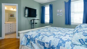 Ein Schlafzimmer mit Bett, Fernseher und einem Fenster mit Vorhängen.