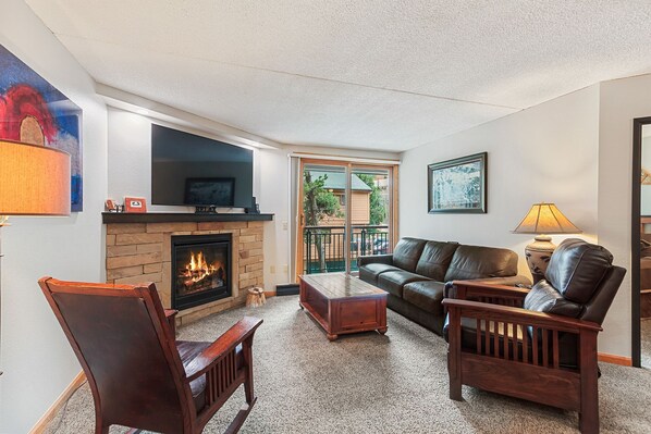 A living room with a fireplace, a sofa, a coffee table, and a TV mounted above the fireplace. - Breckenridge Ski-In/Ski-Out located in Downtown Breckenridge! Pool/Hot Tub Acces (Breckenridge)