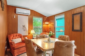 A dining area with a wooden table, chairs, and a vase with flowers. - The Coop at Canyon Lake I Pool & Ideal for Families (Wimberley)