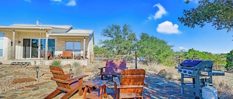 Un patio con mobiliario exterior, una parrilla y un sendero de piedra.