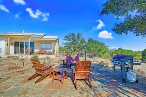 Une terrasse avec des meubles d’extérieur, un barbecue et un chemin en pierre.