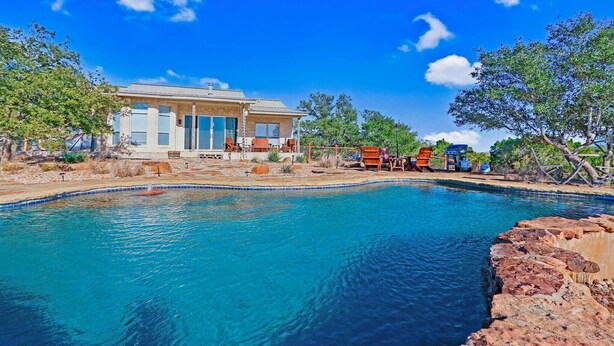 Ein großes Haus mit Swimmingpool, umgeben von Bäumen und blauem Himmel.