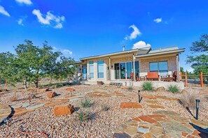 Une maison moderne dotée d’un patio en pierre, d’un espace salon extérieur et surplombant un ciel d’un bleu éclatant.