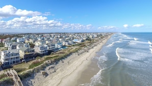 A coastal residential area with houses along the beach, a sandy shoreline, and waves crashing onto the shore. - Terning Point - Corolla, Crown Point, Oceanfront, 20 Yds to Beach, Pool, Hot Tub, Pets OK (Corolla)
