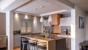 Una cocina moderna con una isla central, electrodomésticos de acero inoxidable y luces colgantes.