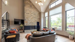 Una sala de estar moderna con chimenea de piedra, un sofá grande y un televisor de pantalla plana.