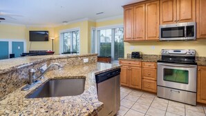 A kitchen with granite countertops, stainless steel appliances, wooden cabinets, and a dishwasher.