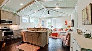 Una cocina amplia con electrodomésticos modernos, una isla grande y una zona de estar acogedora con sofá y cojines decorativos.