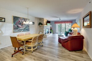 A modern living room with a dining area, a fireplace, and a large window.