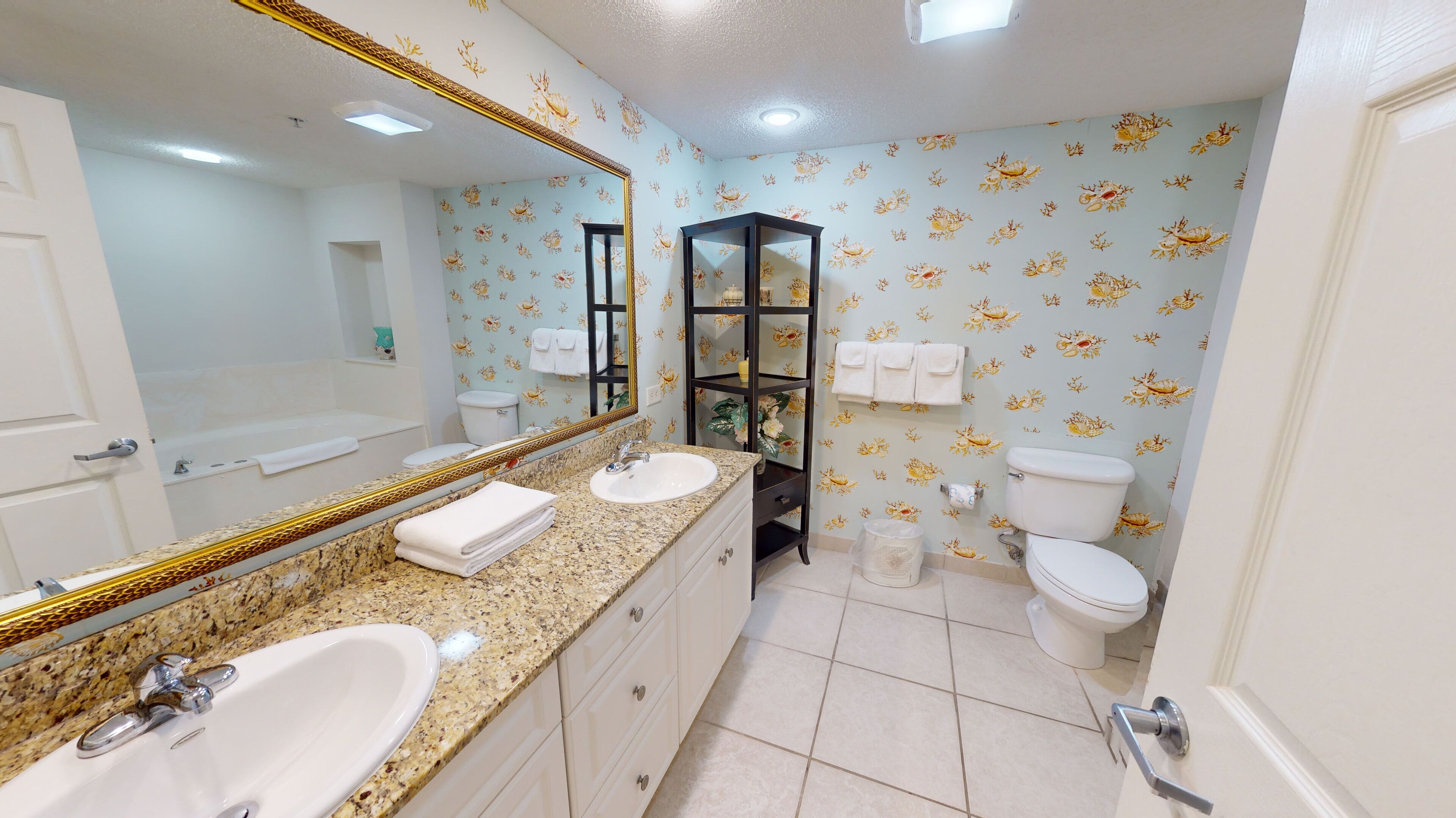 A bathroom with two sinks, a large mirror, a toilet, and a vanity cabinet.