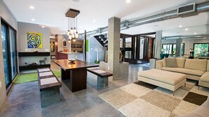 A modern living room with a sofa, a dining table, and a kitchen area.