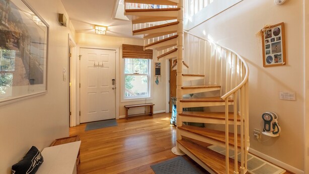 Una escalera de caracol con escalones de madera y barandillas blancas, que conduce a un piso superior.