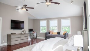 Relax in this serene bedroom with a large bed, sofa, and desk, perfect for working or unwinding.