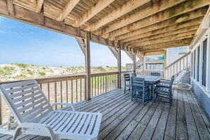 A wooden deck with a table and chairs, overlooking a beach. - Summer Camp - Corolla, Crown Point, Oceanfront, 70 Ft to Beach, Community Pool, Hot Tub, Pets OK (Corolla)