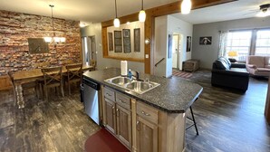 A kitchen with a stone wall, wooden beams, and a dining area with a table and chairs.