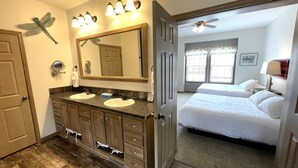 A bathroom with two sinks, a large mirror, and a ceiling fan.